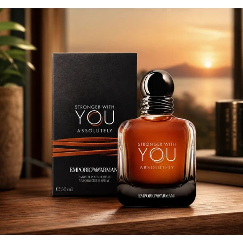 Emporio Armani Stronger With You Absolutely amber bottle beside its black box on a wooden table