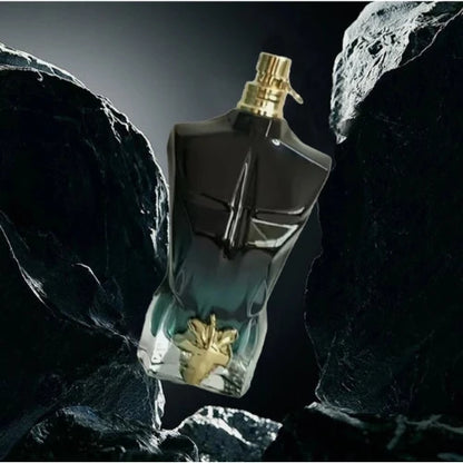 Teal and black sculpted Eau de Parfum bottle with gold leaf detail photographed between dark rocks